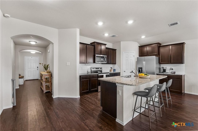 2020 Mallard Ct, Copperas Cove, TX 76522 - kitchen featuring appliances with stainless steel finishes, dark wood-style floors, dark brown cabinets, arched walkways, and a kitchen breakfast bar