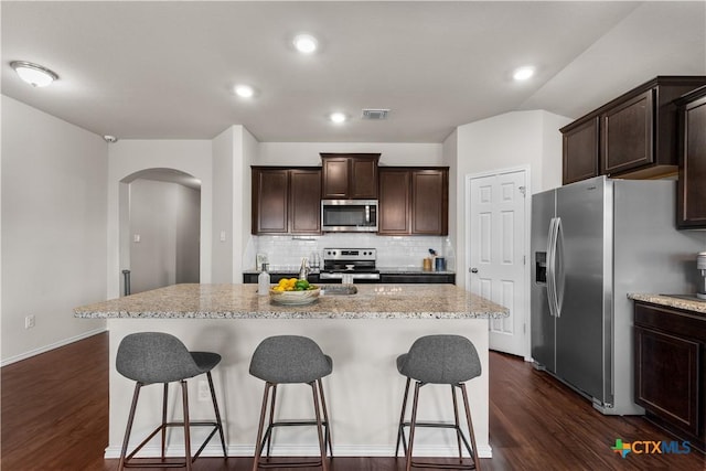 2020 Mallard Ct, Copperas Cove, TX 76522 - kitchen featuring stainless steel appliances, arched walkways, a kitchen bar, dark wood-type flooring, and backsplash