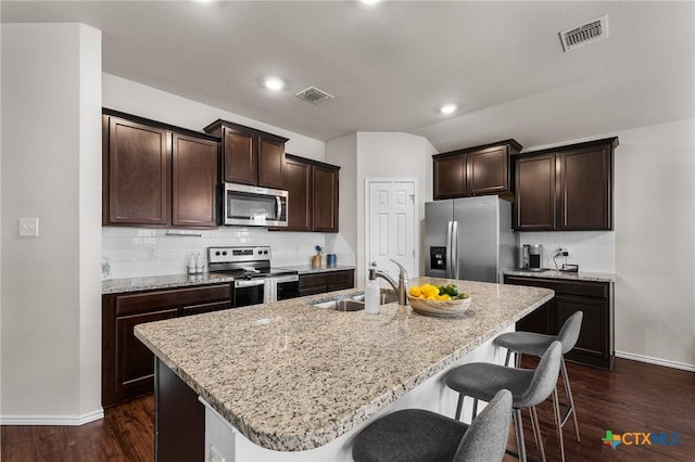 2020 Mallard Ct, Copperas Cove, TX 76522 - kitchen featuring stainless steel appliances, dark brown cabinetry, a breakfast bar, backsplash, and vaulted ceiling