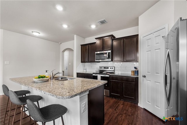 2020 Mallard Ct, Copperas Cove, TX 76522 - kitchen with appliances with stainless steel finishes, arched walkways, a kitchen breakfast bar, light stone countertops, and decorative backsplash