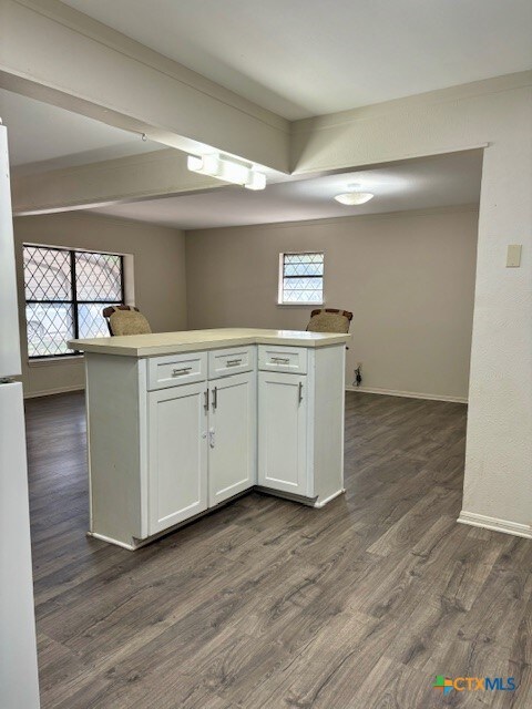 kitchen with kitchen peninsula, white cabinetry, and dark hardwood / wood-style flooring