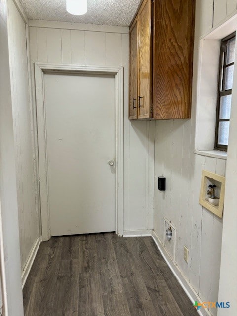 laundry area featuring dark hardwood / wood-style flooring, wood walls, washer hookup, and cabinets