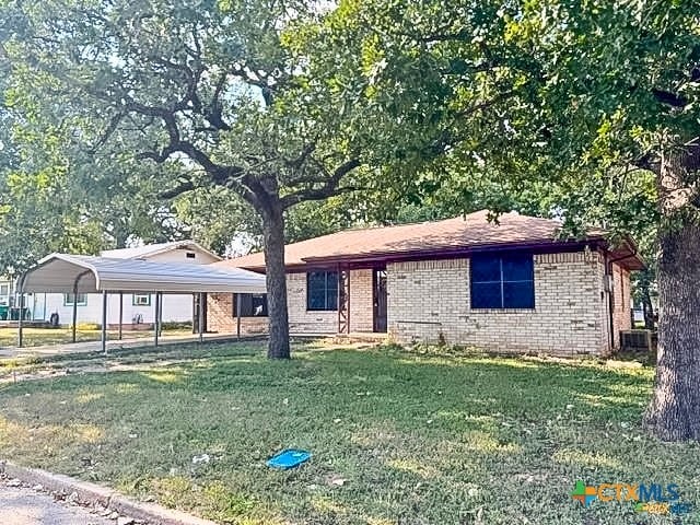 ranch-style house with cooling unit, a front yard, and a carport