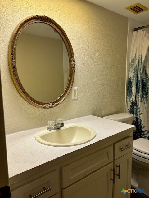 bathroom featuring toilet, vanity, and walk in shower