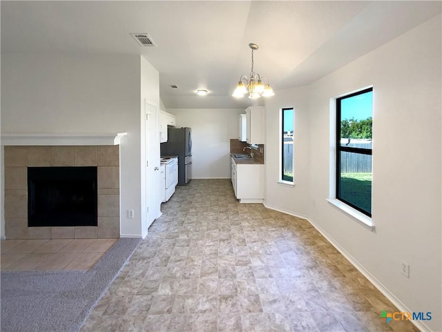 1116 Marlee Cir, Copperas Cove, TX 76522 - kitchen with white cabinetry, a chandelier, freestanding refrigerator, electric range, and a tiled fireplace