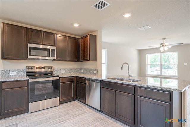 kitchen featuring stainless steel appliances, a peninsula, a sink, visible vents, and dark brown cabinetry