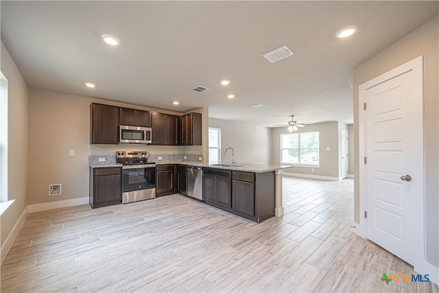 kitchen with stainless steel appliances, baseboards, visible vents, and a sink