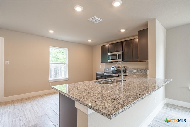 kitchen with light stone counters, dark brown cabinetry, baseboards, appliances with stainless steel finishes, and visible vents