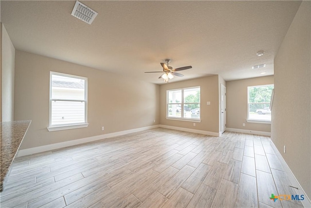 unfurnished room with baseboards, a ceiling fan, visible vents, and light wood-style flooring