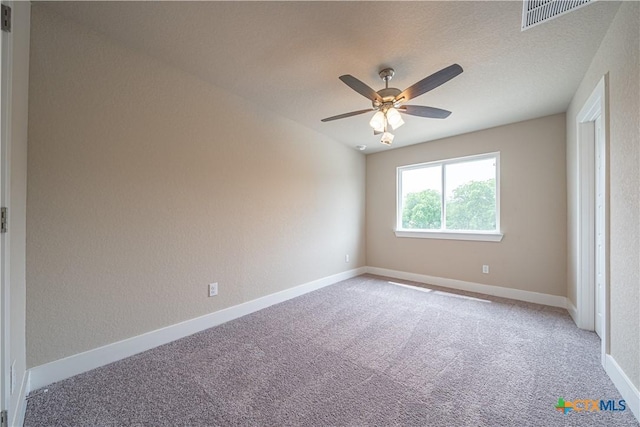 carpeted spare room featuring baseboards, a ceiling fan, and visible vents