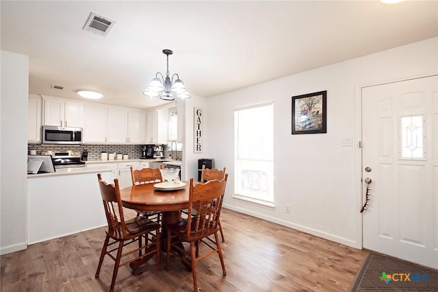 dining space featuring sink, an inviting chandelier, and light hardwood / wood-style flooring