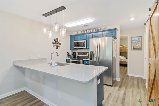 kitchen featuring blue cabinetry, kitchen peninsula, a barn door, and stainless steel appliances