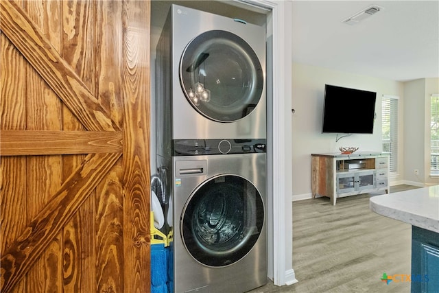 clothes washing area featuring hardwood / wood-style floors and stacked washer / dryer