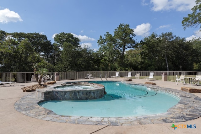 view of swimming pool with a hot tub and a patio