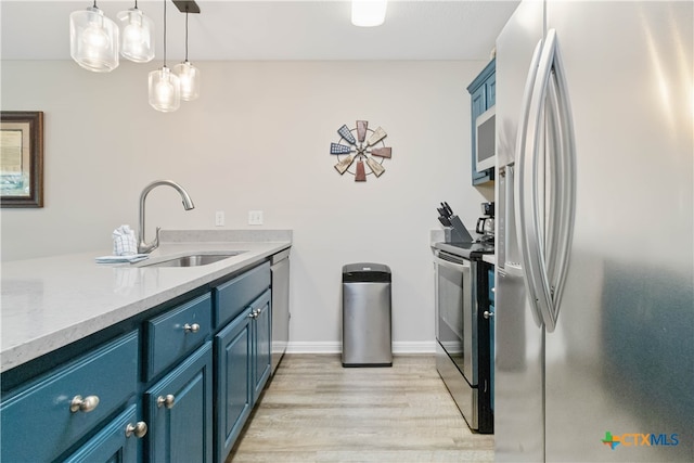 kitchen with blue cabinetry, appliances with stainless steel finishes, decorative light fixtures, sink, and light hardwood / wood-style floors