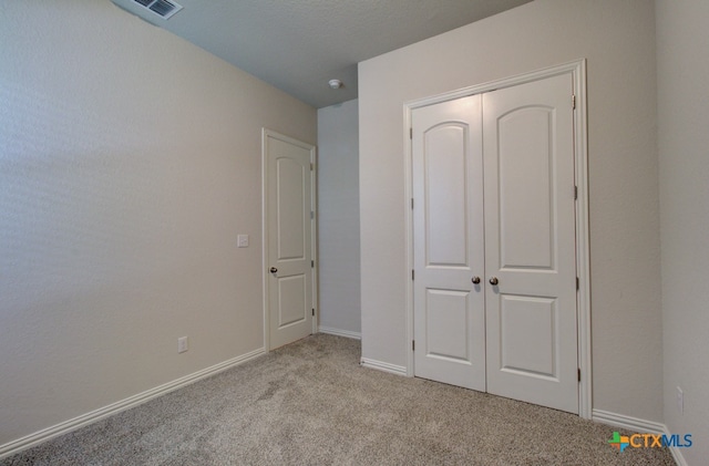 unfurnished bedroom featuring a closet, a textured ceiling, and light colored carpet