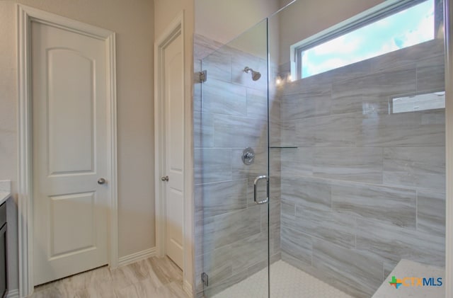 bathroom featuring a shower with shower door and vanity