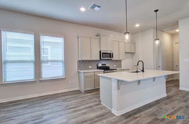 kitchen featuring stainless steel appliances, sink, light hardwood / wood-style flooring, and decorative light fixtures