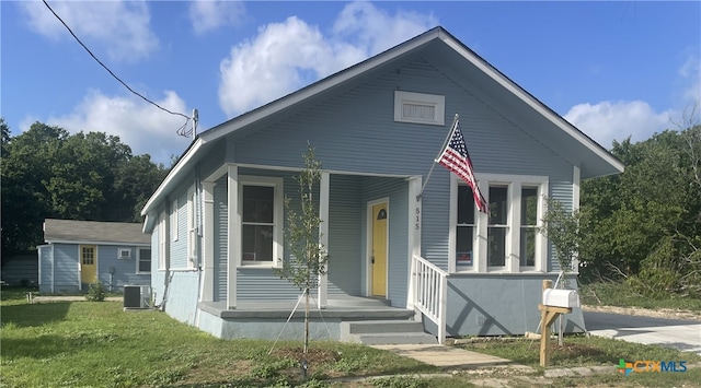 bungalow featuring central air condition unit, a porch, and a front lawn