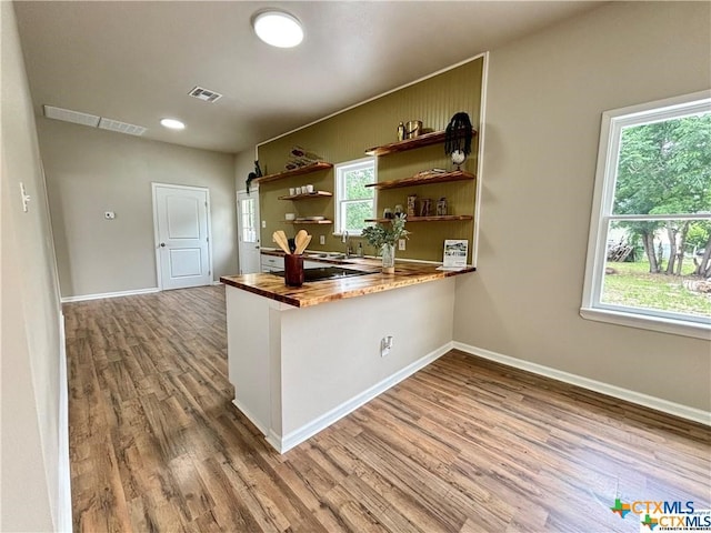 kitchen with butcher block counters, kitchen peninsula, and wood-type flooring