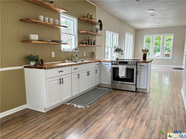 kitchen with dark wood-type flooring, stainless steel range with electric stovetop, a healthy amount of sunlight, and white cabinets