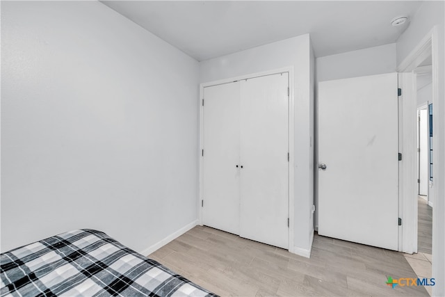 unfurnished bedroom with light hardwood / wood-style flooring and a closet