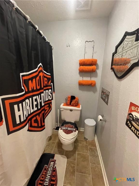 110 Idylwood Pl, Victoria, TX 77901 - full bath featuring toilet, tile patterned floors, a shower with shower curtain, and a textured ceiling