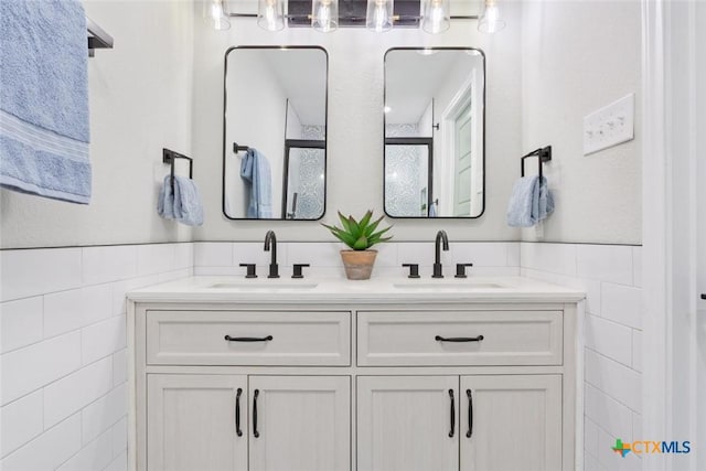2302 Brooklawn Dr, Temple, TX 76502 - full bathroom with tile walls, double vanity, a wainscoted wall, and a shower with door