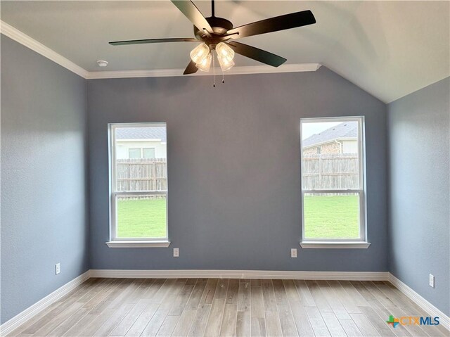 spare room with light wood-style flooring, healthy amount of natural light, a ceiling fan, vaulted ceiling, and crown molding