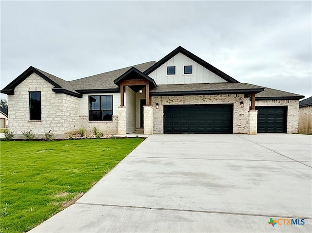view of front of property featuring an attached garage, driveway, a front lawn, board and batten siding, and stone siding