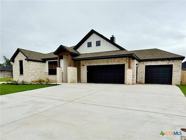 view of front facade with an attached garage, board and batten siding, concrete driveway, a chimney, and a shingled roof