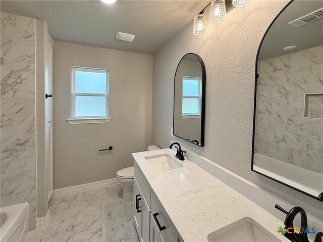 full bathroom with marble look tiles, toilet, a bathtub, double vanity, and baseboards