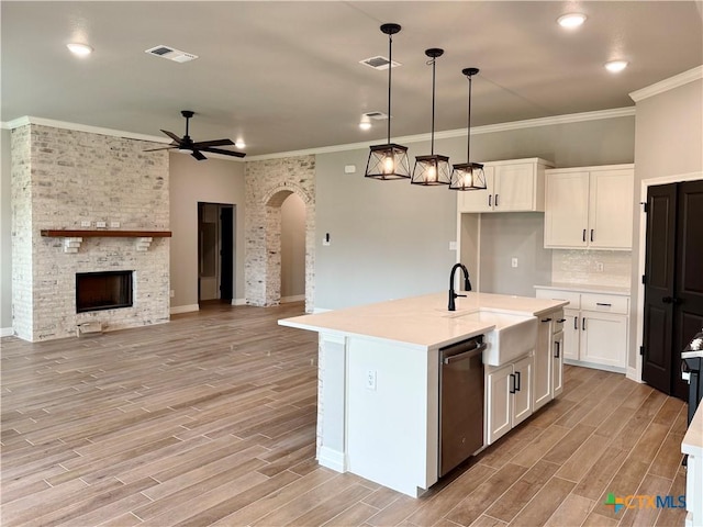 kitchen with stainless steel dishwasher, arched walkways, ceiling fan, a sink, and white cabinetry