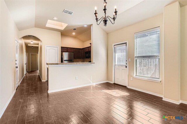 101 Creekside Villa Dr, Kyle, TX 78640 - kitchen featuring freestanding refrigerator, arched walkways, black microwave, vaulted ceiling, and dark brown cabinets