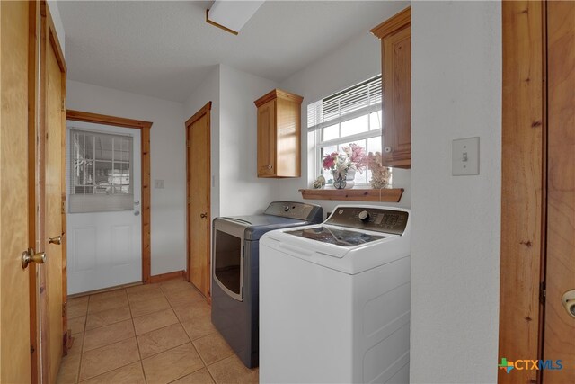 laundry area with cabinets, light tile patterned floors, and washer and clothes dryer