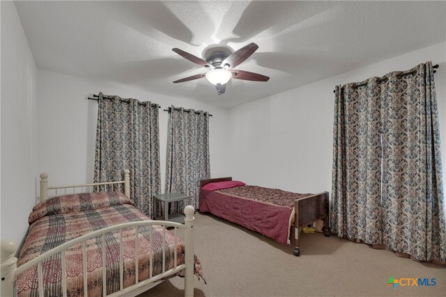 bedroom with ceiling fan, a textured ceiling, and carpet floors