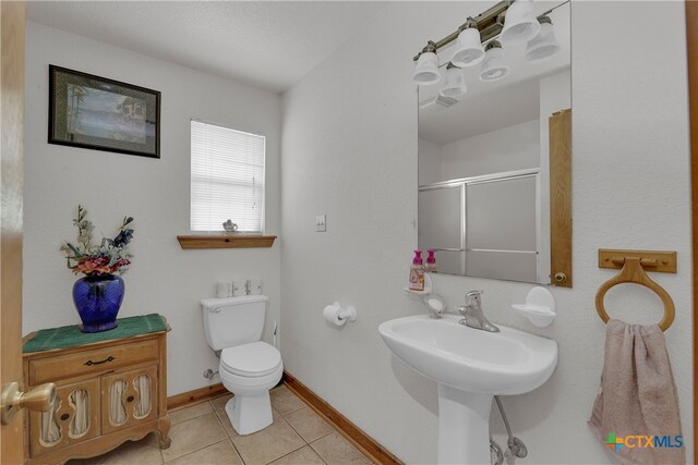 bathroom featuring toilet, an enclosed shower, and tile patterned flooring