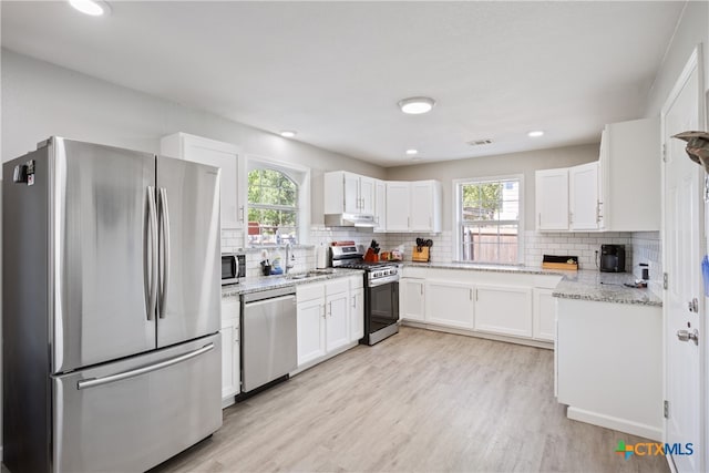 kitchen featuring white cabinets, light wood-type flooring, a wealth of natural light, and stainless steel appliances