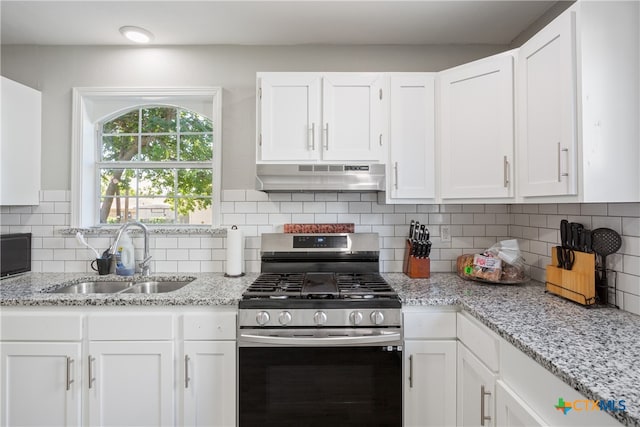 kitchen with tasteful backsplash, white cabinetry, exhaust hood, sink, and stainless steel range with gas stovetop