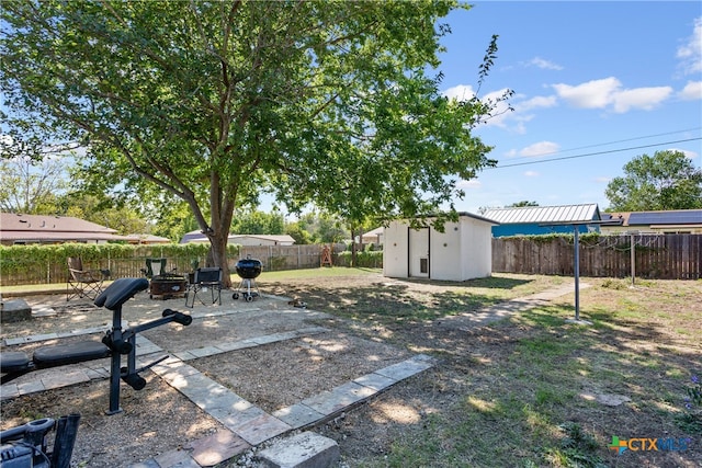 view of yard with a shed, a patio, and a fire pit