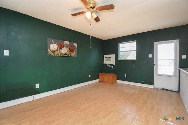 127 S Mesquite Dr, Victoria, TX 77905 - spare room with wood finished floors, a ceiling fan, baseboards, an accent wall, and a wall mounted air conditioner