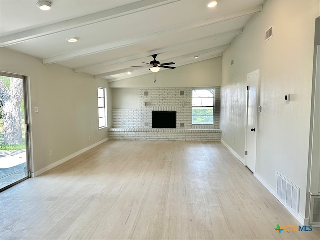 unfurnished living room featuring a fireplace, lofted ceiling with beams, light hardwood / wood-style floors, and a wealth of natural light