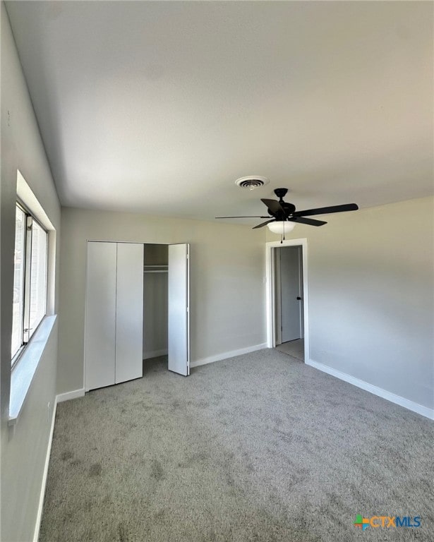 unfurnished bedroom featuring ceiling fan, a closet, and light colored carpet