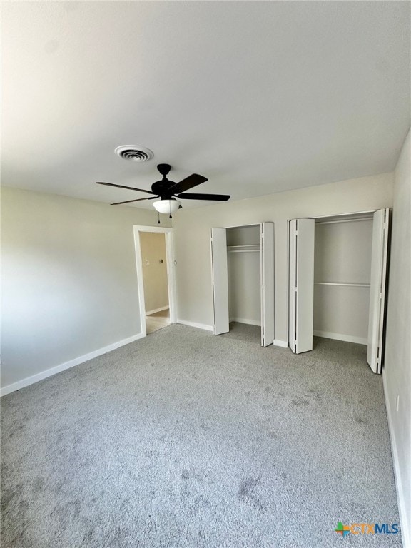 unfurnished bedroom featuring multiple closets, ceiling fan, and light carpet