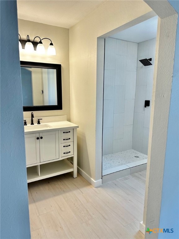 bathroom featuring vanity, wood-type flooring, and tiled shower