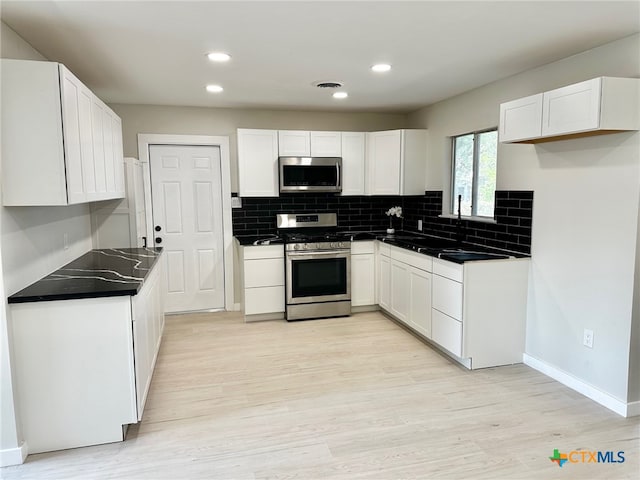 kitchen featuring white cabinets, decorative backsplash, light wood-type flooring, and stainless steel appliances