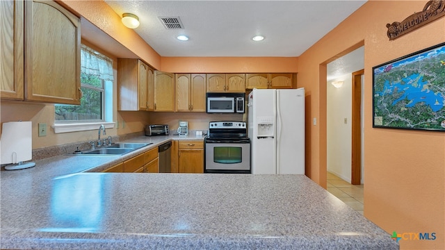 kitchen featuring appliances with stainless steel finishes, light tile patterned floors, light brown cabinets, sink, and kitchen peninsula