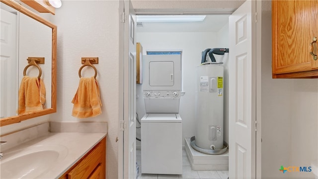 bathroom with tile patterned flooring, water heater, vanity, and stacked washer and clothes dryer