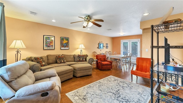 living room featuring hardwood / wood-style floors, ceiling fan, a textured ceiling, and french doors