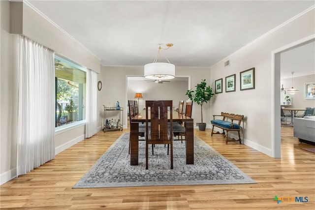 dining area with ornamental molding and light hardwood / wood-style floors